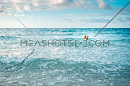 mother and son alone in the turquoise ocean,mom hugs her son,copy space.