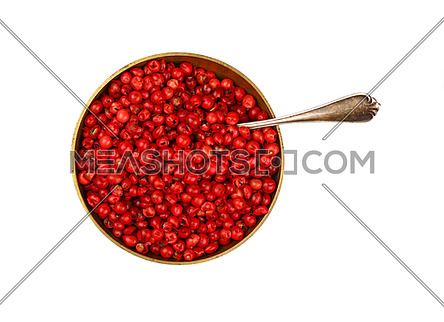 Close up one bronze metal bowl full of red pink pepper peppercorns with spoon isolated on white background, elevated top view, directly above