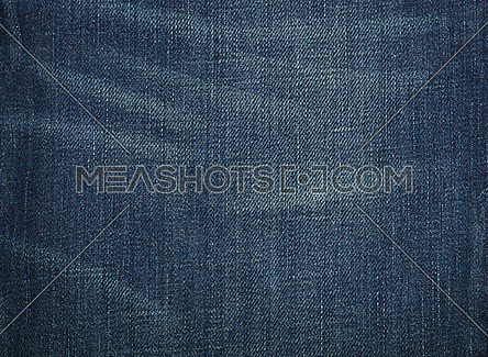 Dark indigo blue washed cotton jeans denim texture background with worn stains, close up