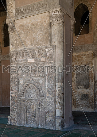 Ornate engraved stone wall with floral patterns and calligraphy in front of the foundation stone of Ahmed Ibn Tulun Mosque with engraved formation text, Cairo, Egypt