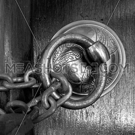 Closeup of antique copper ornate door knocker over an aged wooden door and rusted chain, Eyup Sultan Mosque, Istanbul, Turkey
