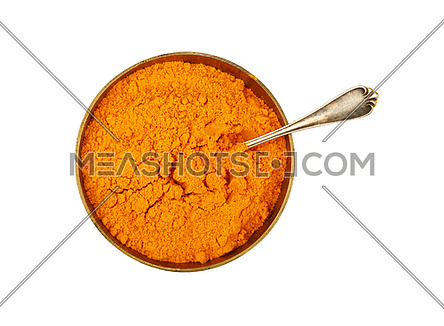 Close up one bronze metal bowl full of yellow turmeric powder spice with spoon isolated on white background, elevated top view, directly above