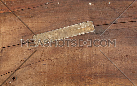Grunge background texture of brown wood with dirty stains, scratches, cracks and nailed tin metal patch, close up