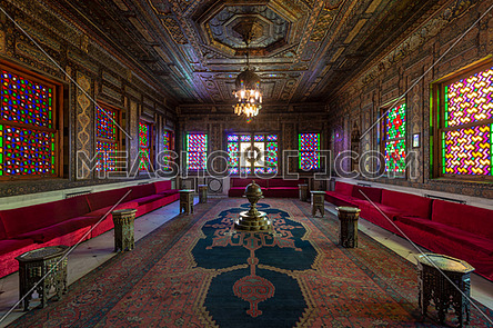 Manial Palace of Prince Mohammed Ali - Open for public. Syrian Hall with ornate wooden wall and ceiling, windows with colored stained glass and Ottoman Empire logo, Cairo, Egypt