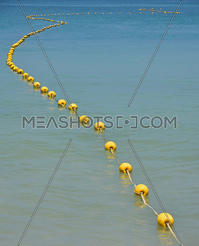 Chain of yellow buoys in blue sea water-112967