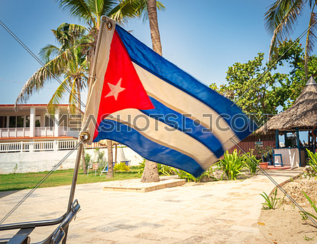 Cuban flag placed in the back of the bike with gardens and beach background, during the sunny day