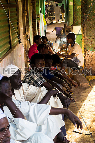 A group of sudanese men and boys sitting on the floor