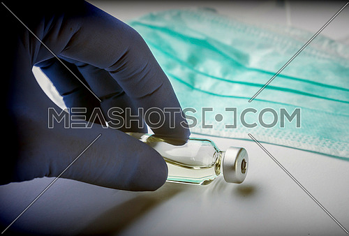 Scientist with blue latex gloves holds vials of test in laboratory for analysis