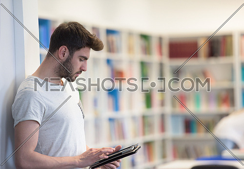 student preparing exam and learning lessons in school library, making research on tablet  and browse internet