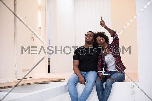 Happy young African American couple having break during moving to new house