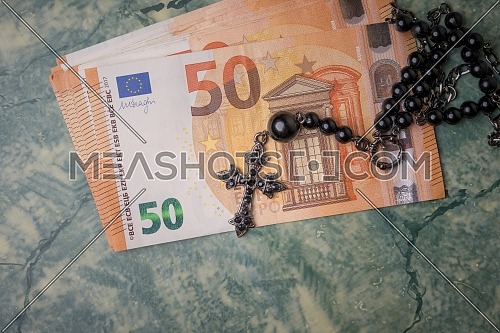 Black rosary and euro money on green table,concept photo.