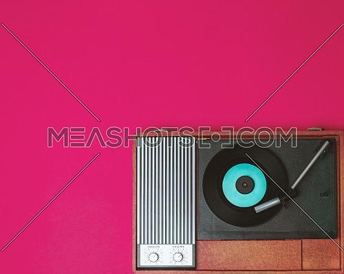 Old vinyl player and turnable on a fuchsia background. Entertainment 70s. Listen to music. Top view.