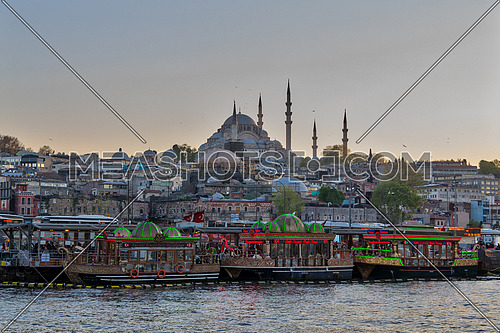 Istanbul, Turkey - April 25, 2017: Traditional fast food bobbing boats serving fish sandwiches at Eminonu district with Rustem Pasha Mosque and Suleymaniye Mosque in the background before sunset