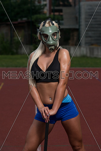 Portrait Of A Physically Fit Young Woman With Hammer And Gas Mask