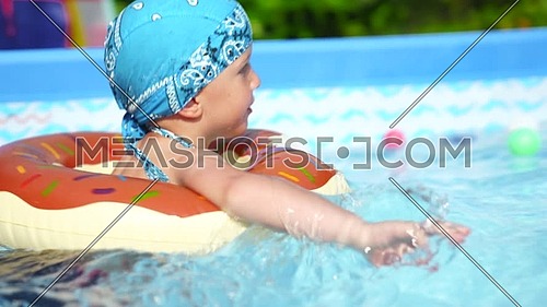 Mom and baby play happily in the small pool.Sunny day, family and summer concept