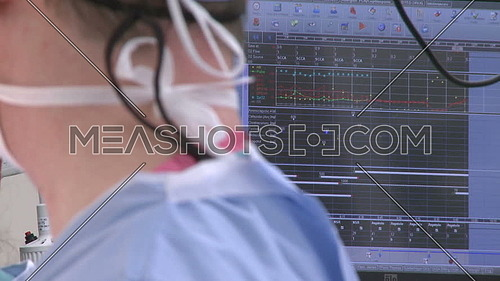 Close shot for Surgical technician head wearing Surgical cap in front of Vital statistics monitor