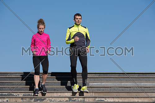 healthy young  couple jogging on steps  at early morning