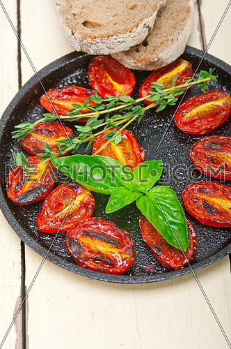 oven baked cherry tomatoes with basil and  thyme on a cast iron skillet