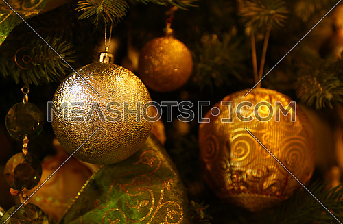 Close up handmade decorations hanging Christmas tree, bows, balls, spheres in warm light, front view