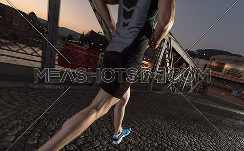 urban sports, young healthy man jogging across the bridge in the city at early morning in night