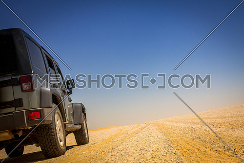 4x4 vechile on an off road track with yellow gravel and a blue sky