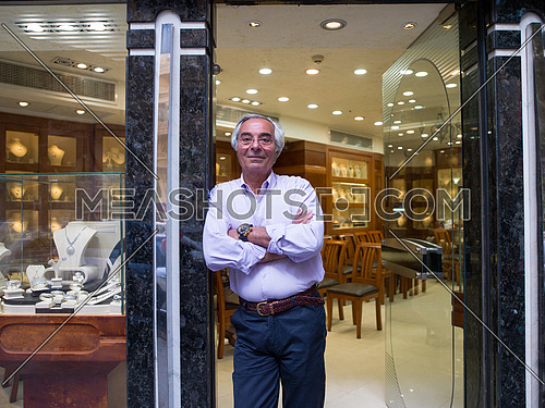portrait of an elderly middle eastern successful owner who stands at the door of his luxury jewelry store