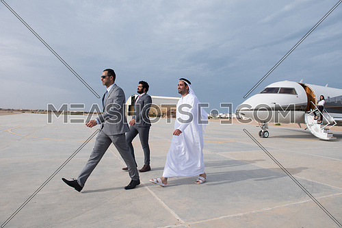 young successful businessmen walking with their Arab business partner in front of private airplane