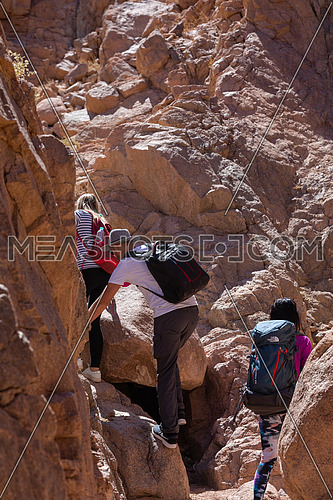 Long shot for group of tourists walking on big rocks explore Sinai Mountain for wadi Freij at day.