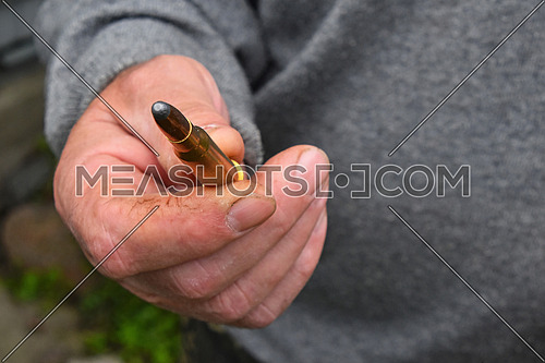 Old man hand holding and showing one 7.62 mm caliber ammunition bullet