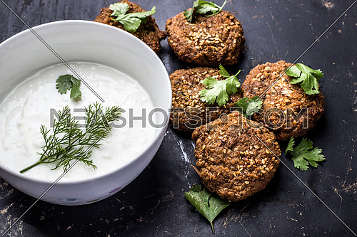 Falafel put on a table top beside a bowl of yogurt
Falafel is a traditional Middle Eastern food, commonly served in a pita, which acts as a pocket, or wrapped in a flatbread known as tameya