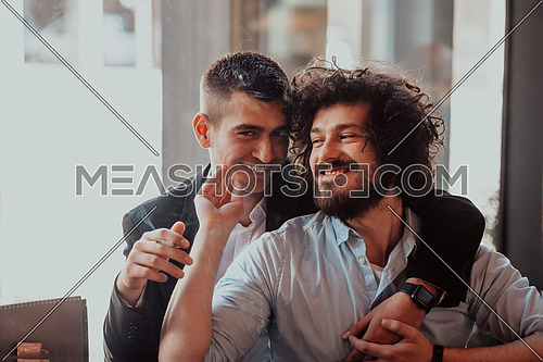 two lgbt guys sit romantically embracing in a modern cafe while smoking cigars