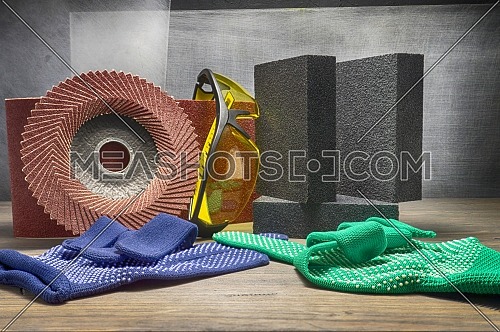 Different tools for sanding - sanding belt, abrasive sponge and flap disc for angle grinder, safety gloves and goggles, renovation, safety and health at work concept