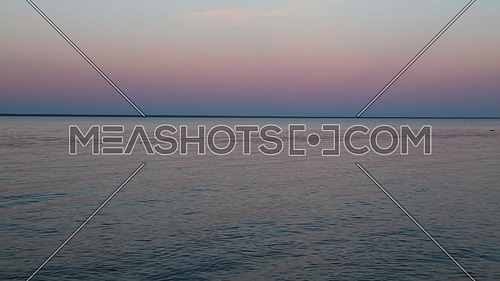 Waterscape of waves and ripples run in the wind on blue water surface of lake under clear purple and pink evening sunset sky, high angle view