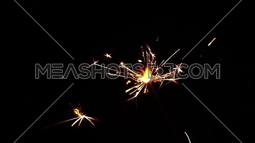 Close up one firework sparkler over black background, low angle side view