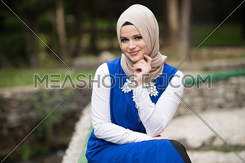 Portrait Of Young Muslim Woman Sitting On Bench In Park