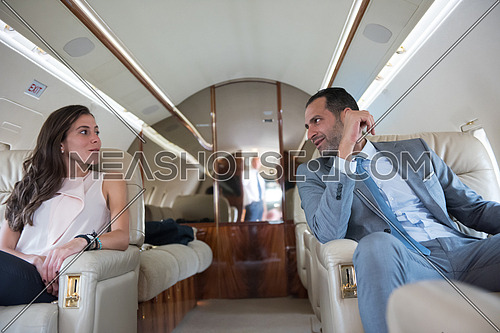 Young middle eastern successful businessman and businesswoman enjoy sitting in private jet