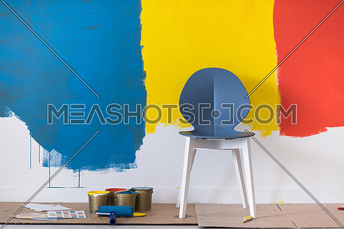 empty chair and equipment for painting in front of colorful wall in the background