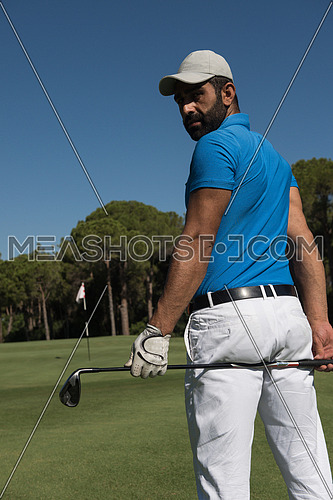 handsome middle eastern golf player portrait from back with course in background  at beautiful sunny day