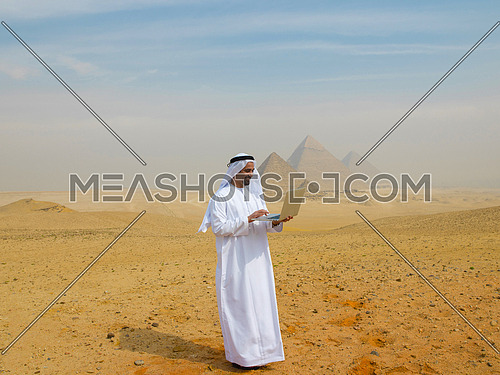 arab business man using laptop computer in desert with great giza pyramids in background