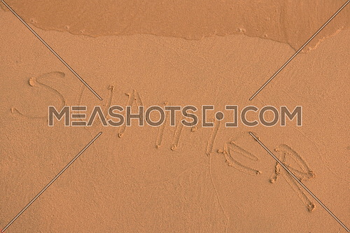 The Word Summer Written in the orange Sand background on a Beach at sunset