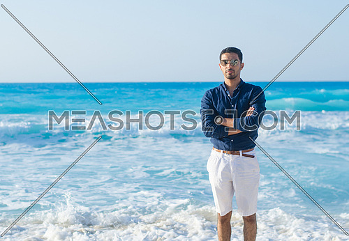 a young man standing by the blue sea