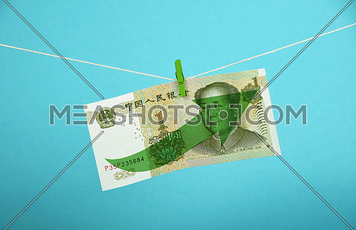 China economy growth, strengthening of Chinese yuan, one yuan banknote with green arrow up hanged ascending with pin at rope over blue