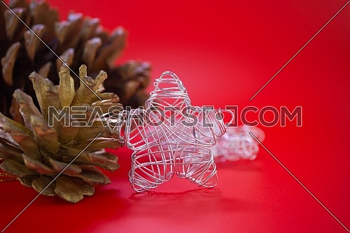 Pine cones and small Christmas decoration silver wire woven star viewed in close-up on red background