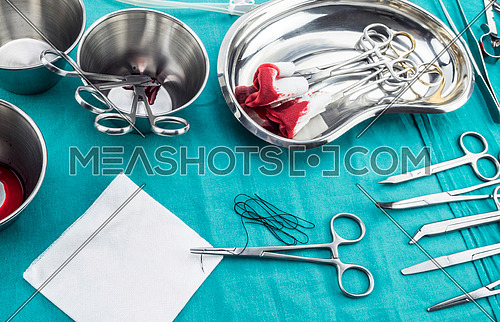 Scissors surgical with torundas soaked with blood on a tray metal in an operating theater, composition horizontal, conceptual image