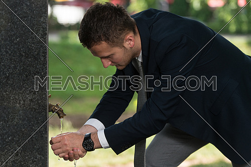 Young Businessman Refreshing Himself By Drinking Water