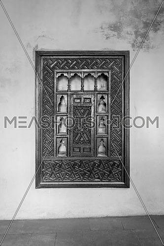 Black and white of wooden arabesque ottoman era cupboard with engraved decorations embedded in a grunge wall, Rosetta City, Egypt