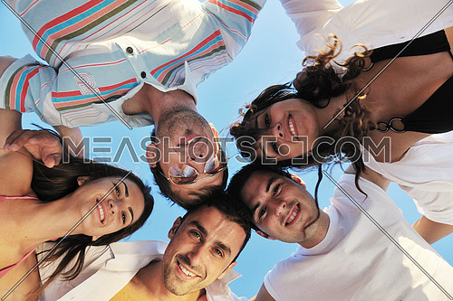 happy young friends group team huging have fun and celebrate  on the beach at the sunset