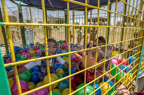 Egyptian kids playing inside a ball den in amusement park during eid al fitr celebration