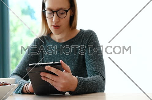 woman using tablet while having food
