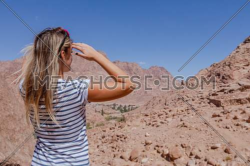 Long shot for a female tourist from behind exploring Sinai Mountain for wadi Freij at day.